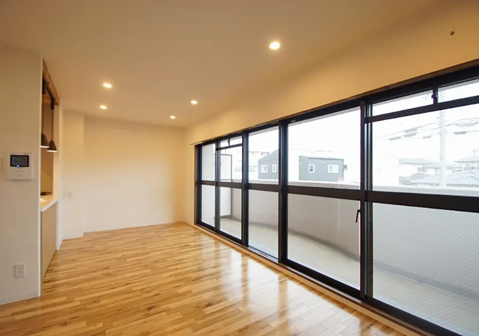 写真:フローリングの床と壁一面の窓、窓の外にはベランダがある