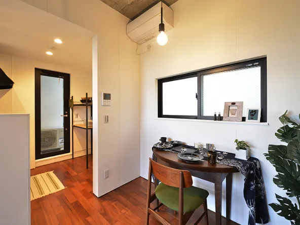 写真:窓のある白い壁に向かって設置してあるテーブル、フローリングの床