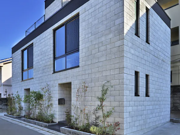 写真:白いブロック状の外壁で飾られてるいる二階建ての住居外観