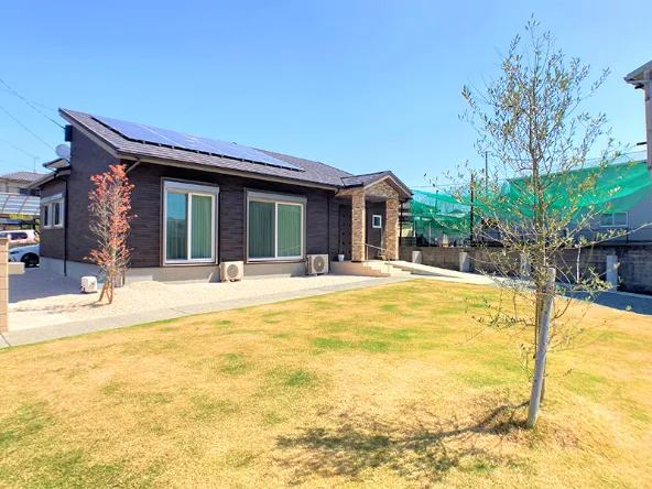 写真:大きな窓が二つある平家の住居と、広い芝生の庭には木が1本植えられている